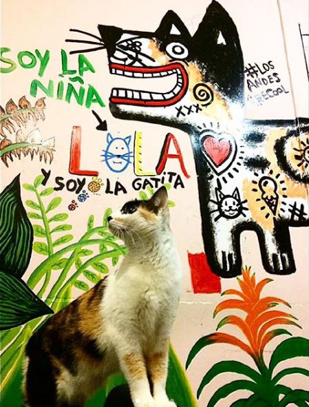 Lola posa delante de su mural