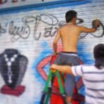 El graffitero David Jiménez pintando la persiana de un local